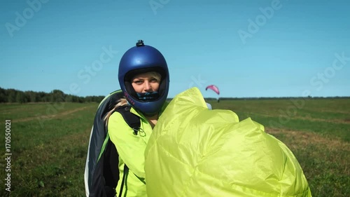 Paragliding girl. Paraglider is ready to take off over a green hill. carries a parachute after landing photo