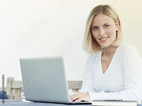 junge blonde Frau arbeitet am Laptop
