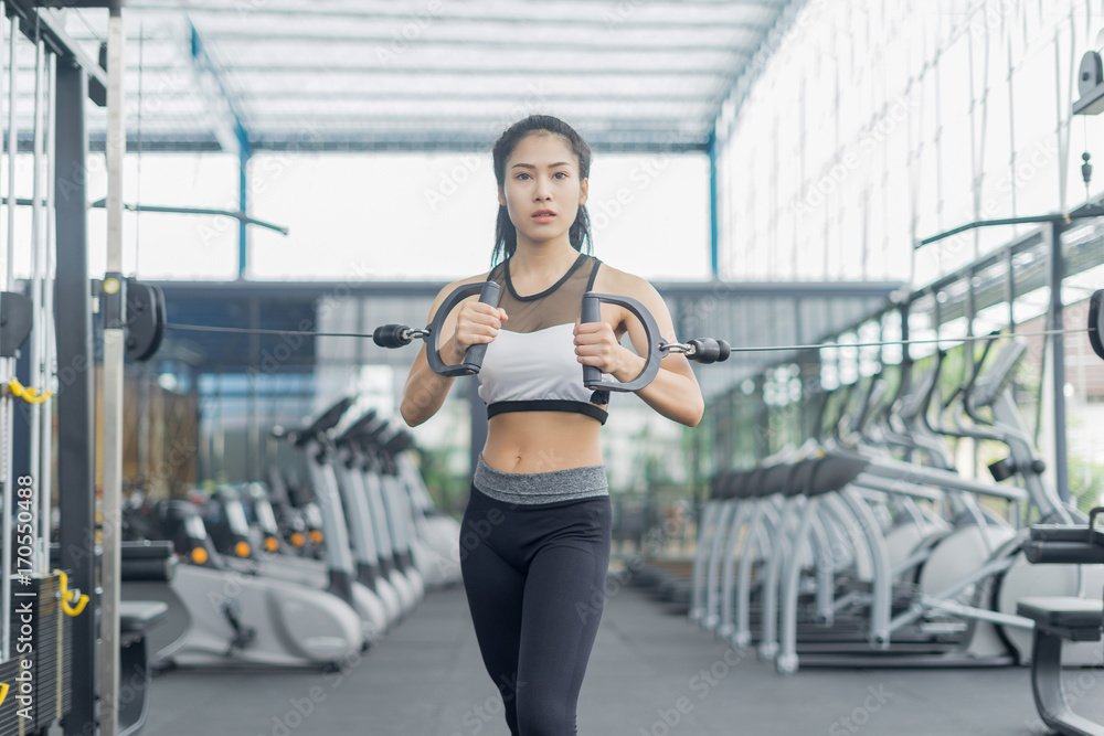 Fototapeta premium Fitness woman in training showing exercises with exercise-machine in gym