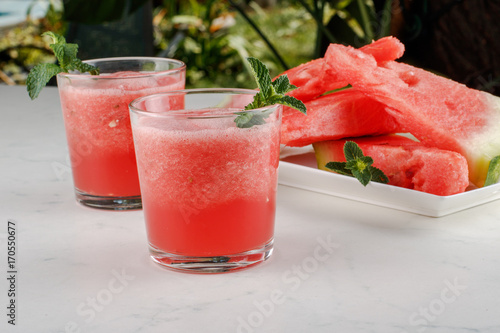 Watermelon smothie and slices with lemon on light gray background