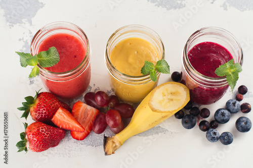 Assortment of bright fruit and berry smoothies on white table. Summer refreshing drinks. Space for text