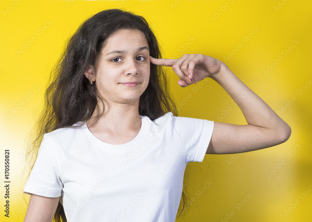 Angry mad young woman gesturing with finger against temple are you crazy?. Isolated on yellow. Angry mad young woman gesturing with finger against temple are you crazy?. Isolated on yellow.
