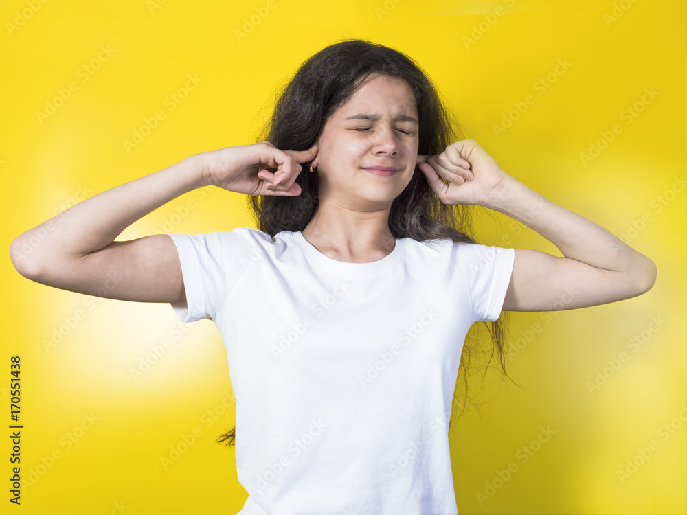 Young woman blocking her ears on a yellow background Young woman blocking her ears on a yellow background