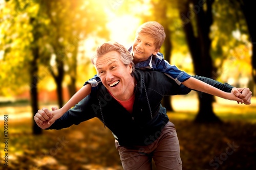 Composite image of father giving his son piggyback ride