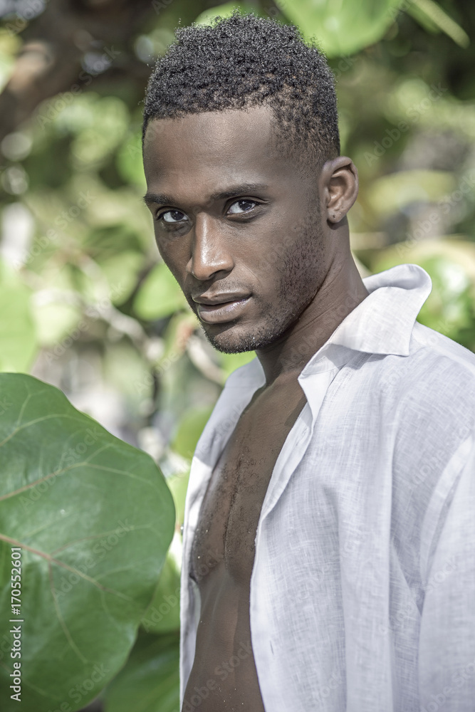 Photo shoot for a black handsome guy on the rocky shore of the ocean. black guy near the tree Photo shoot for a black handsome guy on the rocky shore of the ocean. black guy near the tree