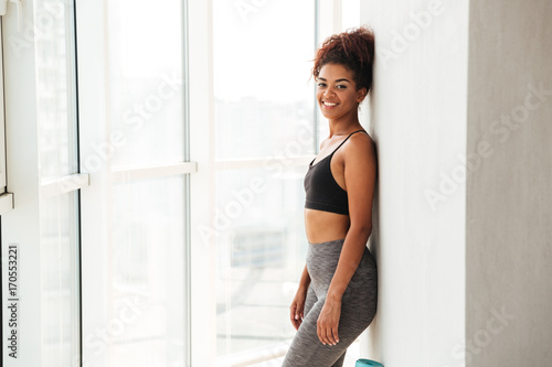 Young woman in sportswear posing near wall