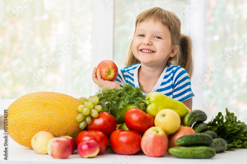 Happy little girl and a lot of fruit and vegetables.