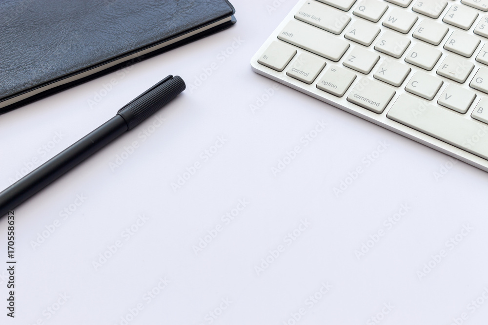 book, pen and computer keyboard on white table with over light and soft-focus in the background book, pen and computer keyboard on white table with over light and soft-focus in the background