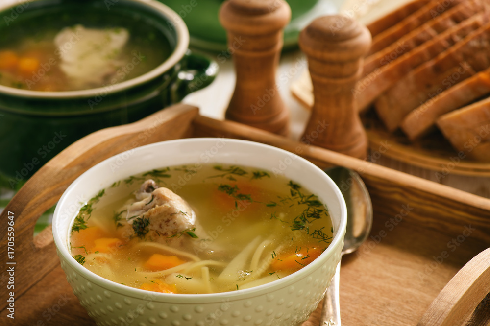 Chicken soup in bowl on wooden tray. Chicken soup in bowl on wooden tray.