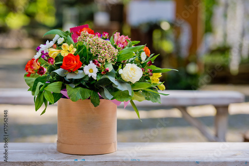 Fototapeta Naklejka Na Ścianę i Meble -  A beautiful gift bouquet in a wooden vase on a wooden bench. Wedding decorations.