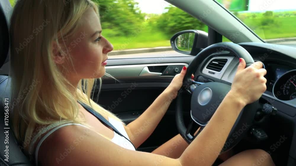 Young attractive blond woman drives a car in summer day - road in countryside Young attractive blond woman drives a car in summer day - road in countryside