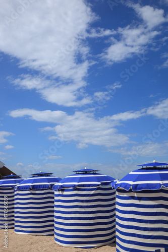beach in summer with tents, sun and blue sky