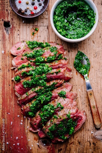 Sliced grilled barbecue beef steak with green chimichurri sauce photo