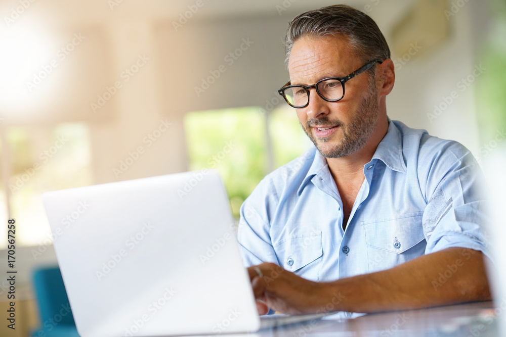 Mature man working on laptop computer at home Mature man working on laptop computer at home