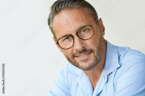 Fototapeta Naklejka Na Ścianę i Meble -  Portrait of mature man with eyeglasses and blue shirt, isolated