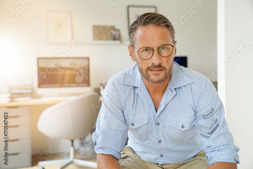 Cheerful mature man sitting in home-office
