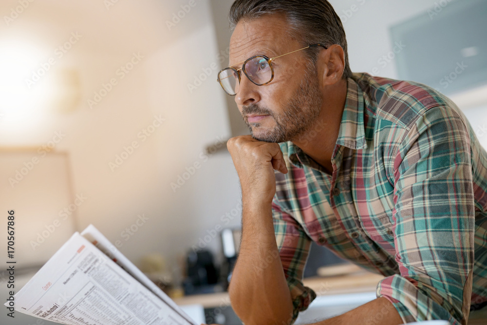 Handsome mature man at home reading newspaper Handsome mature man at home reading newspaper