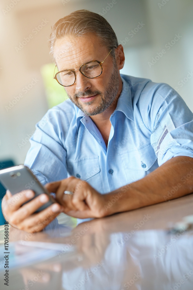 Mature man with eyeglasses typing message on smartphone Mature man with eyeglasses typing message on smartphone