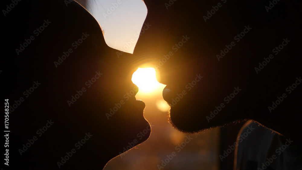 A loving couple man and woman passionately kiss at sunset, catching the effect of the lens from the sun. HD A loving couple man and woman passionately kiss at sunset, catching the effect of the lens from the sun. HD