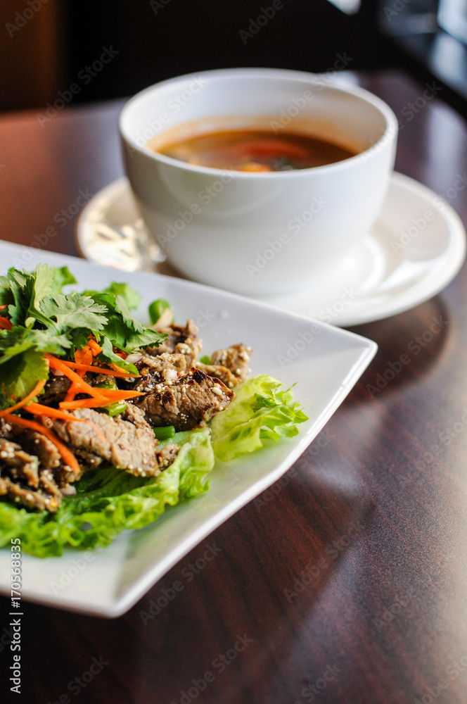 Nam Tok Spicy Beef Salad, Char-broiled tender slices of beef mixed with red onion, green onions, roasted rice, cilantro, chili powder & citrus leaves. Nam Tok Spicy Beef Salad, Char-broiled tender slices of beef mixed with red onion, green onions, roasted rice, cilantro, chili powder & citrus leaves.