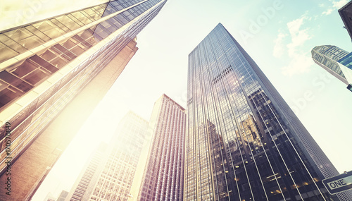 Vintage stylized panoramic picture of Manhattan skyscrapers at sunset, looking up perspective, New York City, USA. 