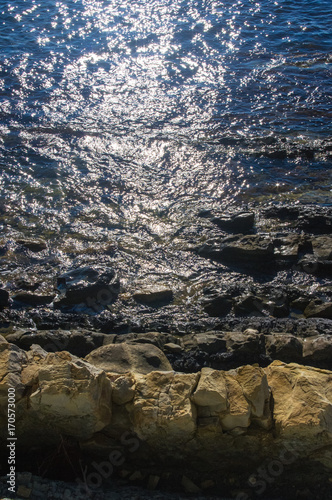 rocky sea shore with pebble beach, waves with foam