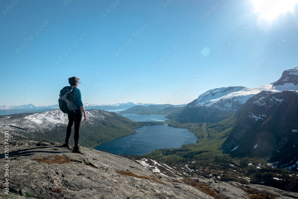 Young female hiker enjoying beautiful view of summer landscape in a nord part of Lofoten Islands, Norway.