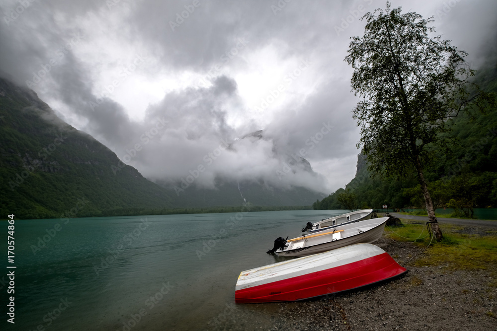 Obraz premium The Norwegian landscape with a boat on lake against mountains.