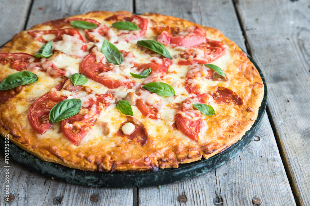 Hot Homemade Pepperoni Pizza on a rustic wooden table. Pizza with tomato, cheese and basil 