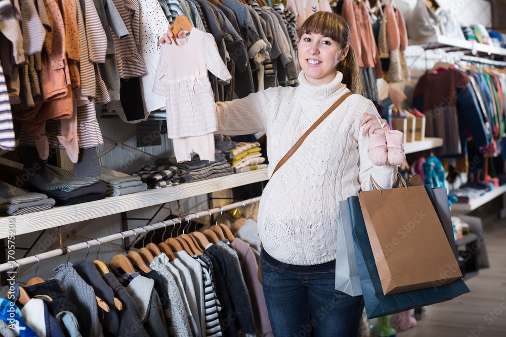Adult pregnant woman choosing clothes for baby