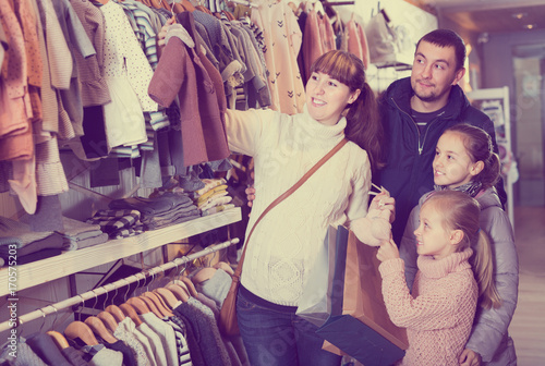 Family with children searching clothes for new baby
