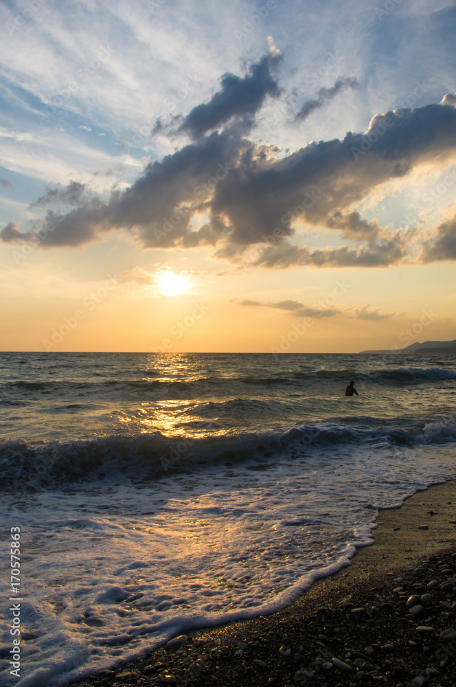 Fototapeta premium Amazing sea sunset on the pebble beach, the sun, waves, clouds