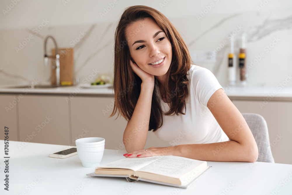 Smiling girl reading a book while sitting at the table Smiling girl reading a book while sitting at the table