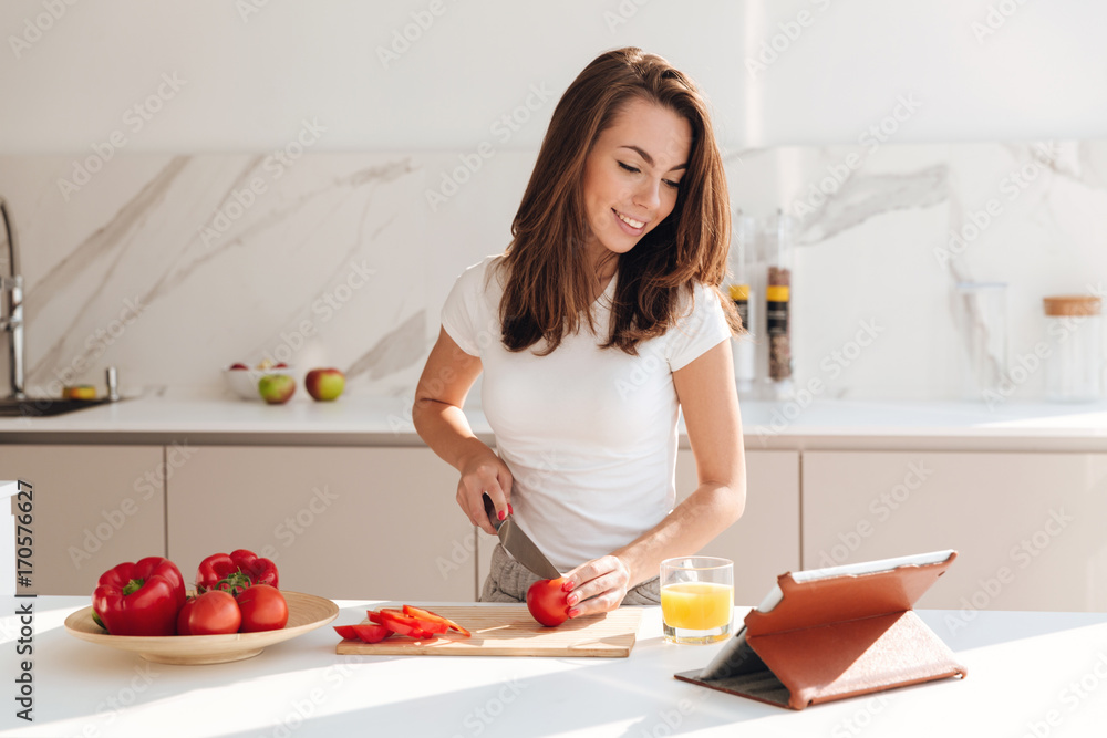 Happy young woman cutting vegetables for the salad Happy young woman cutting vegetables for the salad
