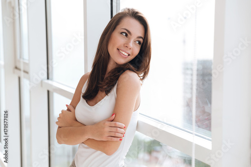 Smiling pretty girl leaning on a window and looking away