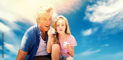 Composite image of a little girl blowing bubbles with her father © vectorfusionart