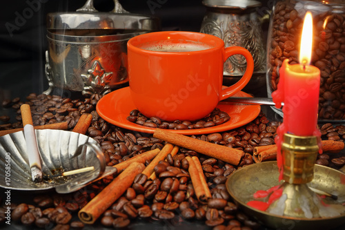 Coffee still life with an orange mug, a cigarette and a candle