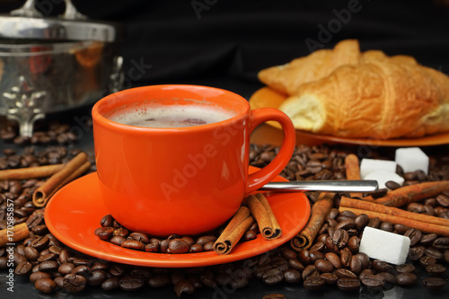 Still life with an orange mug in coffee grains