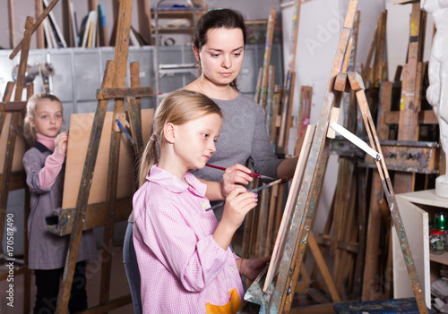 Woman teacher assisting girl during painting class