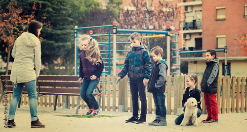 Children playing rubber band jumping game and laughing