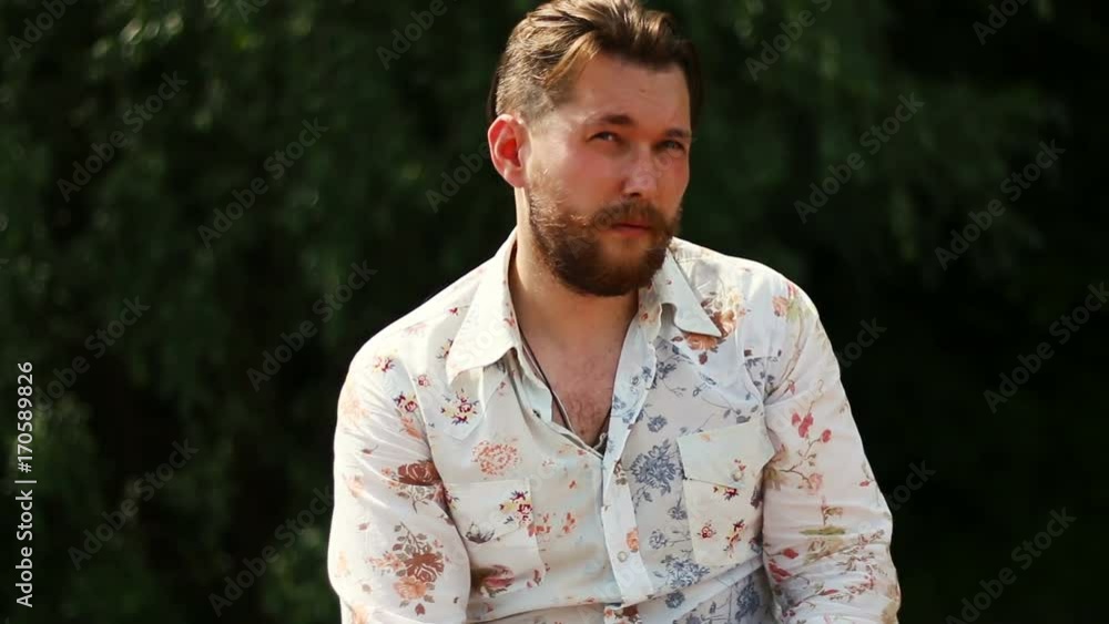 Portrait of attractive young bearded man in shirt looking at the camera outdoors Portrait of attractive young bearded man in shirt looking at the camera outdoors