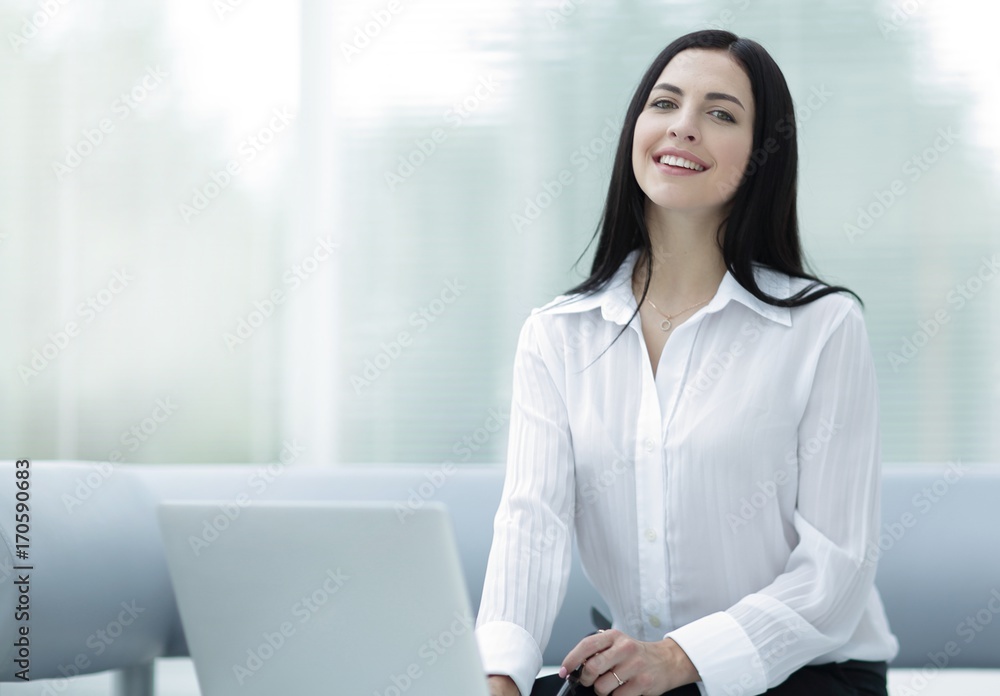 successful young woman sitting at a desk on a blurred background. successful young woman sitting at a desk on a blurred background.