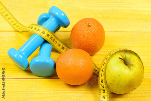 dumbbells weight with measuring tape, apple, orange, diet concept