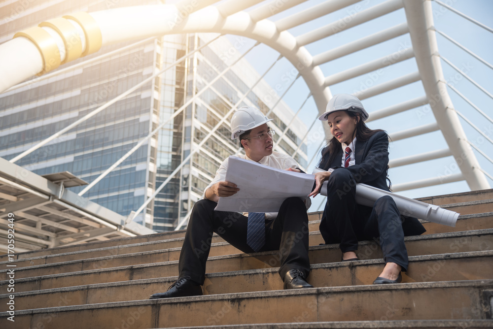 Teamwork of young engineer man and woman working as architects on a building site ,while consult on blueprint at building construction Teamwork of young engineer man and woman working as architects on a building site ,while consult on blueprint at building construction