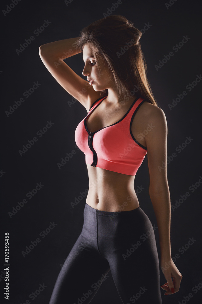 Beautiful fitness girl posing on black background