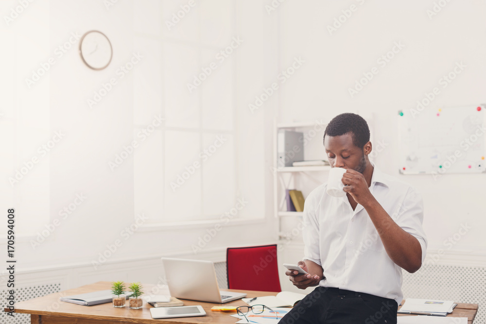 Young black businessman with mobile phone in modern white office Young black businessman with mobile phone in modern white office