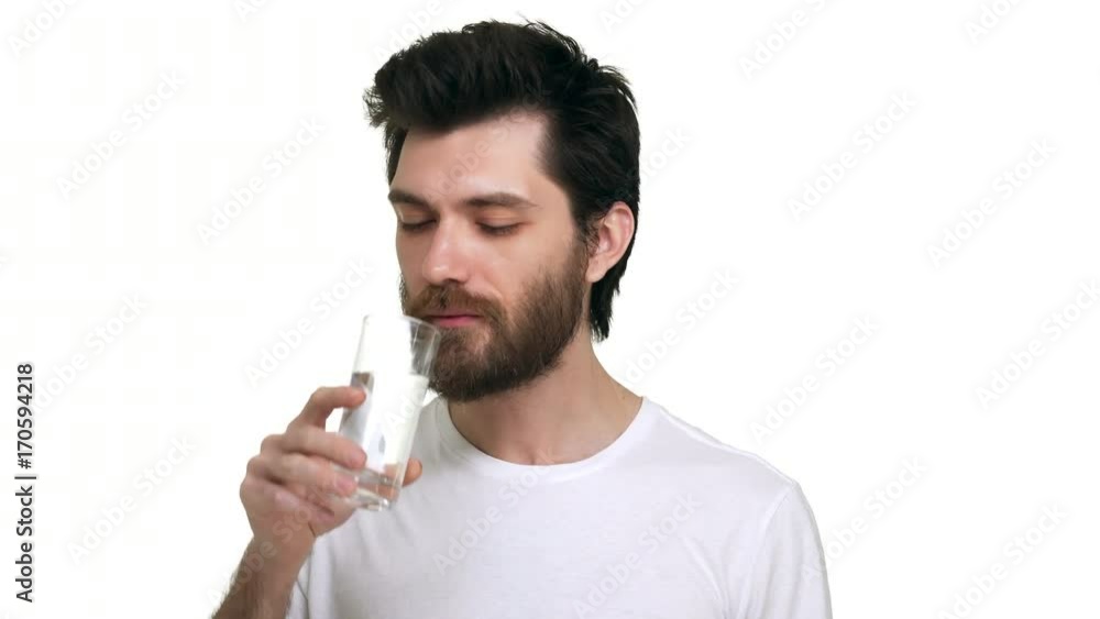 Caucasian male holding a glass of water drinking smiling satisfied on white background Caucasian male holding a glass of water drinking smiling satisfied on white background