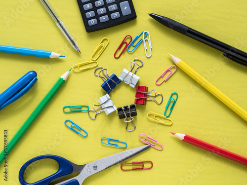 Colorful stationery on yelow background - calculator, scissors, crayon, pencil, pen