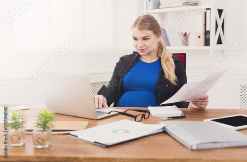 Pregnant business lady at work reading papers