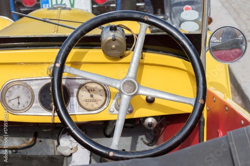 Kutna Hora, Czech Republic - August 18, 2017: Closeup of a yellow dashboard, with speedometer and steering wheel, of a vintage car parked in the historic city center
